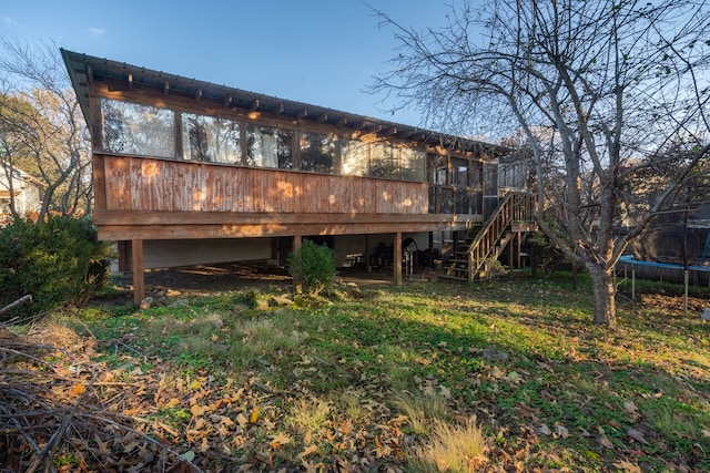 back of house with a deck and a trampoline