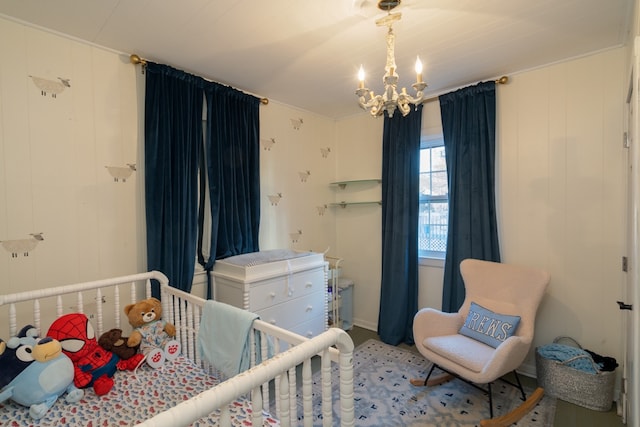 bedroom featuring an inviting chandelier, a nursery area, and wood walls