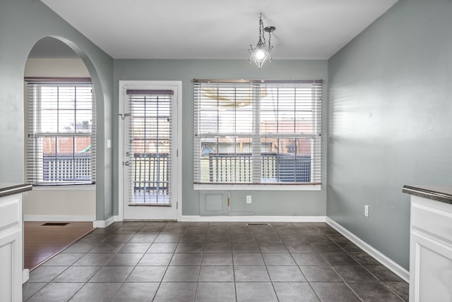 unfurnished dining area featuring dark tile patterned floors