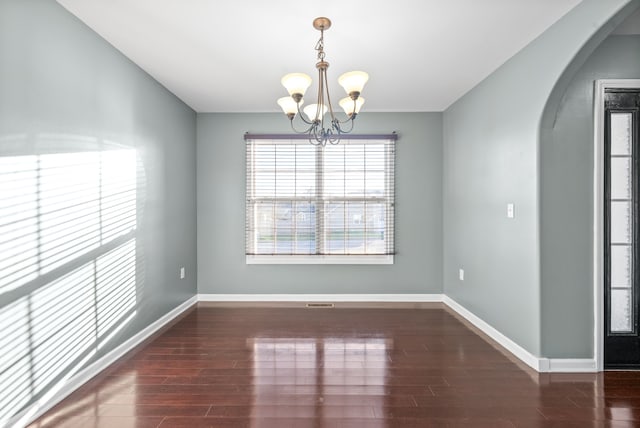 unfurnished dining area featuring dark wood-type flooring and an inviting chandelier