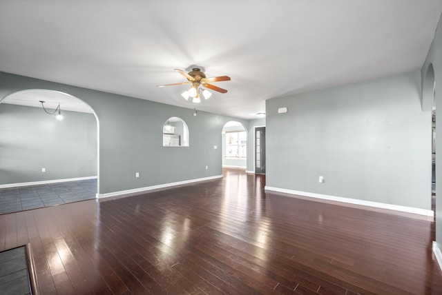 spare room featuring ceiling fan with notable chandelier and dark wood-type flooring