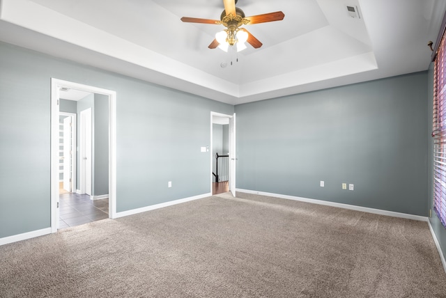 unfurnished room with carpet, a tray ceiling, and ceiling fan