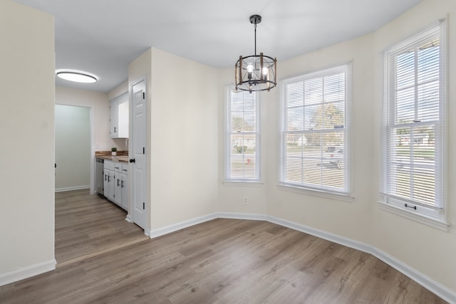 unfurnished dining area with light hardwood / wood-style floors and an inviting chandelier