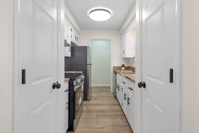 kitchen with light hardwood / wood-style floors, white cabinetry, sink, and appliances with stainless steel finishes