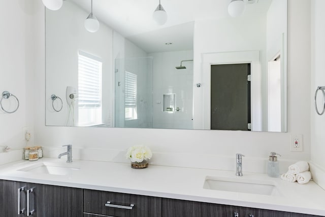 bathroom featuring double vanity, a stall shower, and a sink