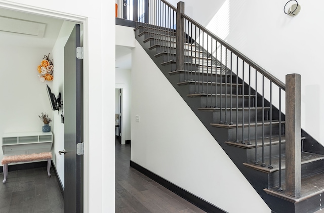 staircase with a high ceiling, wood finished floors, and baseboards