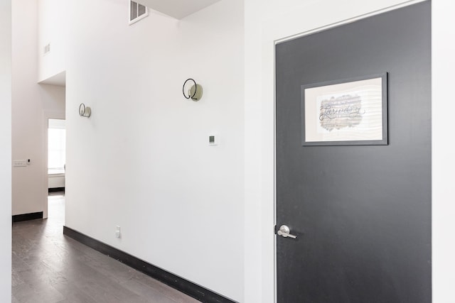 hallway with wood finished floors, visible vents, and baseboards