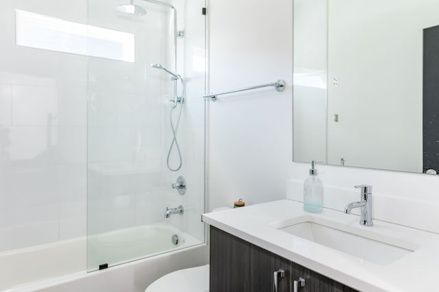 full bathroom featuring vanity, tiled shower / bath combo, and toilet