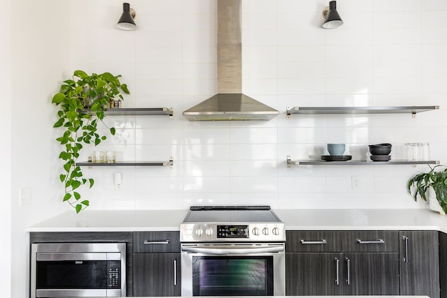 kitchen with open shelves, wall chimney range hood, appliances with stainless steel finishes, light countertops, and decorative backsplash