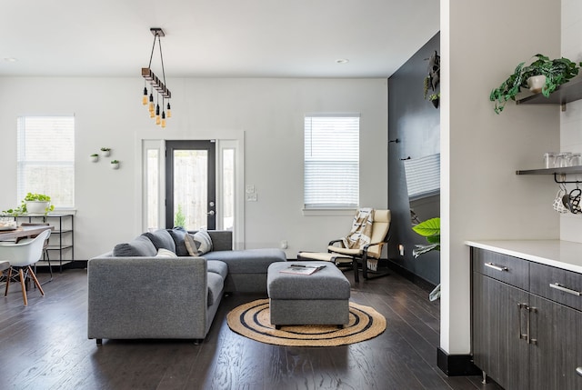 living room featuring dark wood finished floors, baseboards, and a wealth of natural light