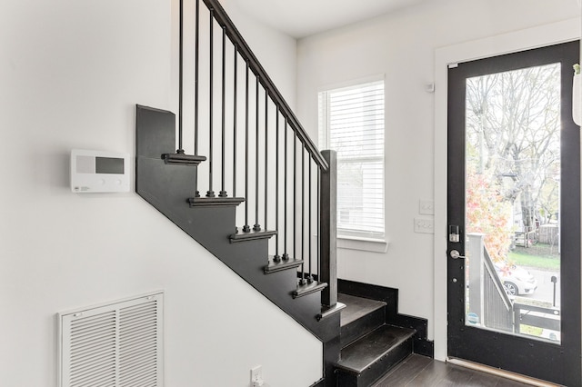 foyer with stairs, wood finished floors, and visible vents