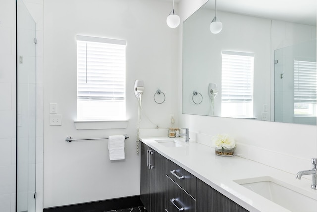 bathroom with a wealth of natural light, a shower with door, and vanity