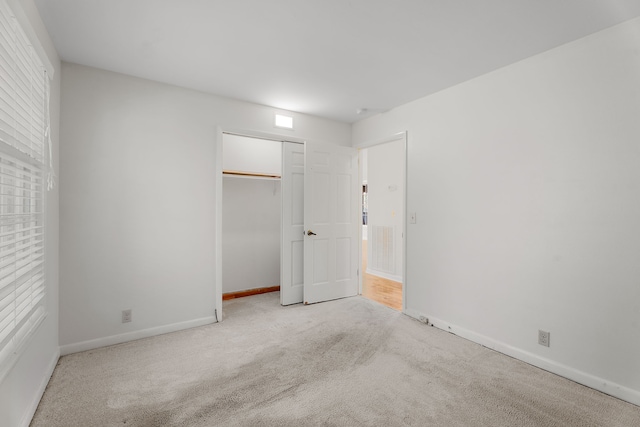 unfurnished bedroom featuring light carpet and a closet