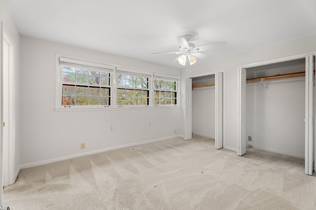 unfurnished bedroom with multiple windows, light colored carpet, and ceiling fan