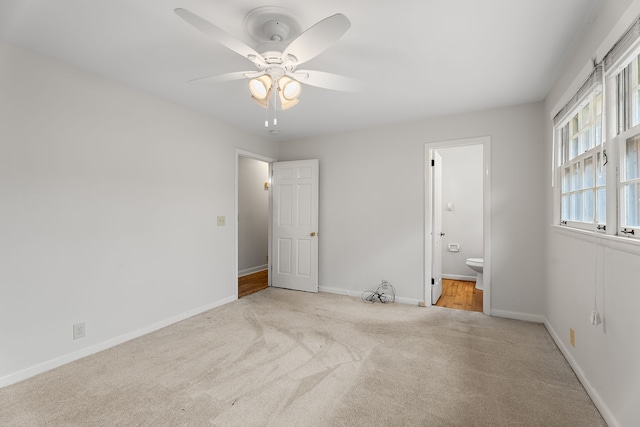 unfurnished bedroom with light carpet, ensuite bathroom, and ceiling fan