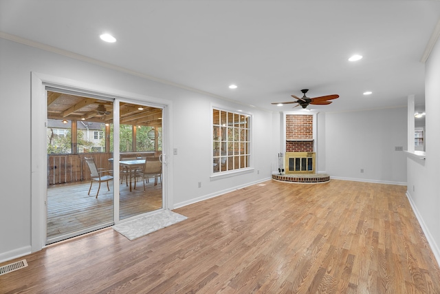 unfurnished living room with a brick fireplace, ceiling fan, crown molding, and light hardwood / wood-style flooring