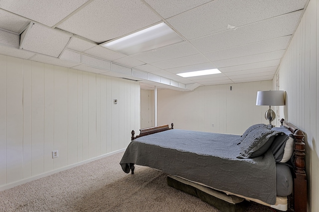 carpeted bedroom with wood walls and a drop ceiling