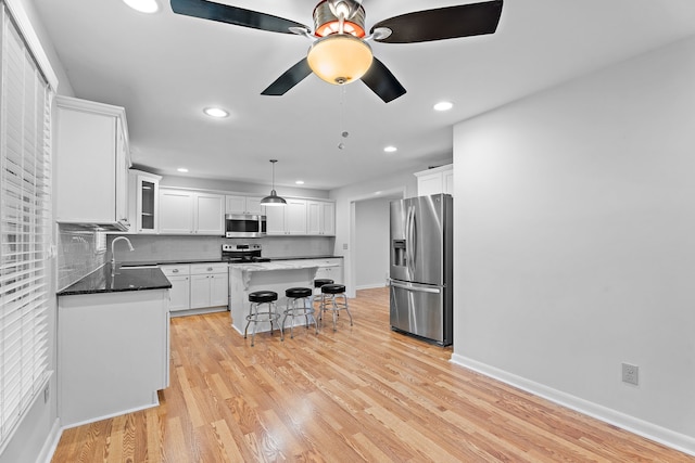 kitchen featuring a breakfast bar, light hardwood / wood-style flooring, a kitchen island, white cabinetry, and stainless steel appliances