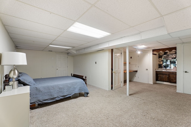 bedroom featuring a paneled ceiling, wood walls, and light carpet