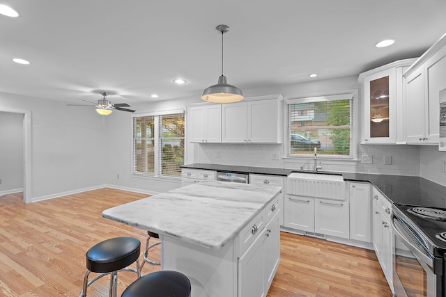 kitchen with a healthy amount of sunlight, white cabinets, pendant lighting, and light hardwood / wood-style floors