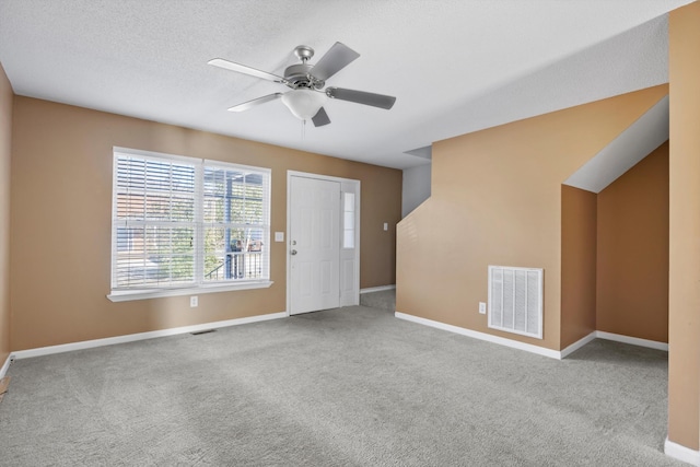 interior space featuring ceiling fan, light colored carpet, and a textured ceiling