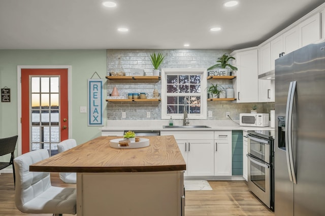 kitchen with appliances with stainless steel finishes, a kitchen breakfast bar, sink, white cabinets, and a center island