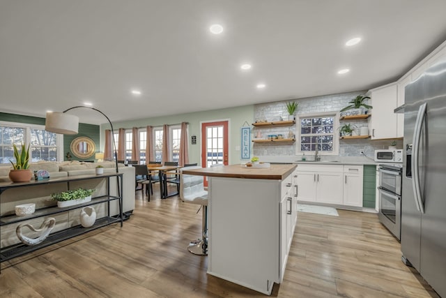 kitchen with a center island, white cabinetry, tasteful backsplash, light hardwood / wood-style floors, and butcher block counters