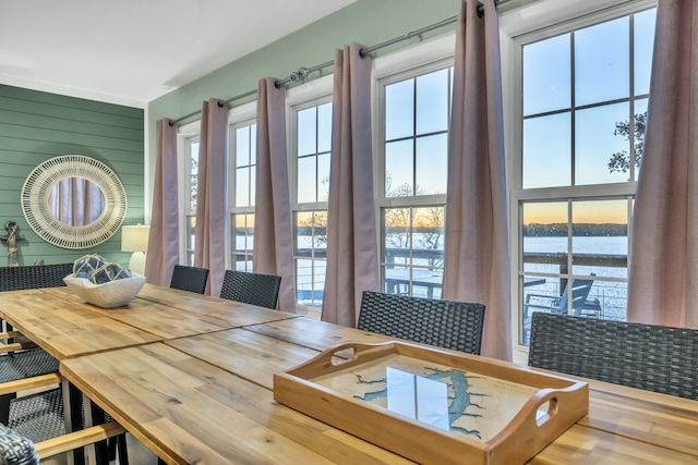 dining room with wooden walls, a water view, and wood-type flooring