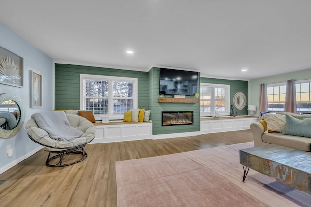 living room featuring a fireplace, light wood-type flooring, and wood walls