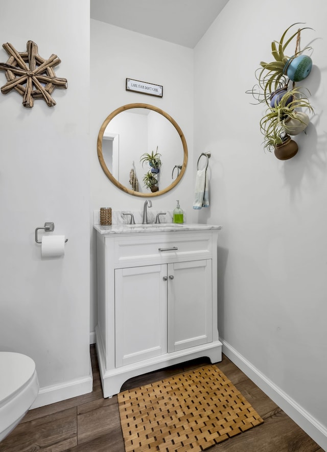 bathroom featuring toilet, vanity, and hardwood / wood-style flooring