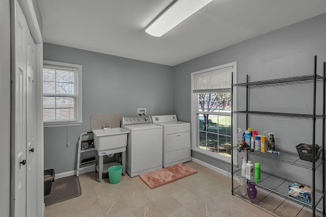 clothes washing area with sink, a wealth of natural light, and washing machine and clothes dryer