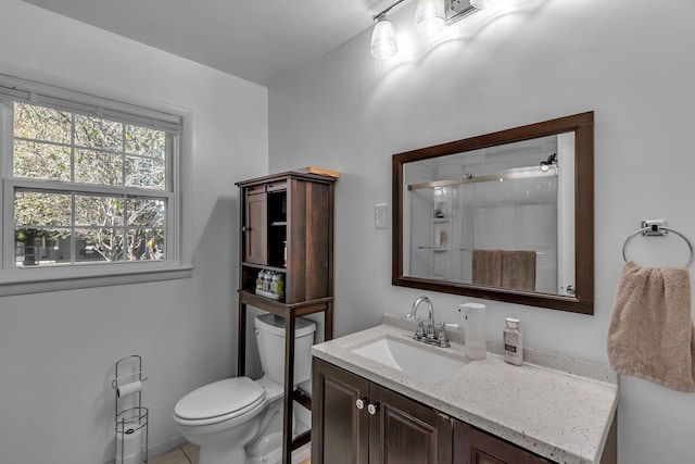 bathroom featuring tile patterned floors, vanity, a shower with shower door, and toilet