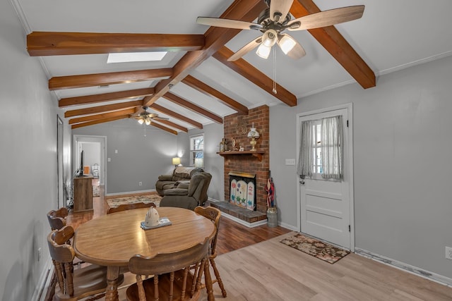 dining space with a healthy amount of sunlight, lofted ceiling with skylight, a fireplace, and light hardwood / wood-style flooring