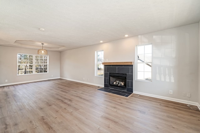 unfurnished living room with a fireplace, a healthy amount of sunlight, a textured ceiling, and hardwood / wood-style flooring