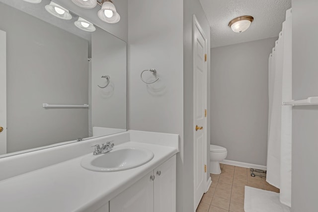 bathroom featuring tile patterned flooring, vanity, toilet, and a textured ceiling