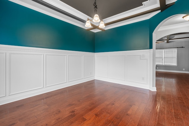 empty room with a raised ceiling, dark hardwood / wood-style flooring, a chandelier, and ornamental molding