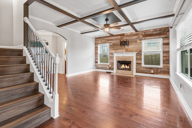 unfurnished living room with ceiling fan, plenty of natural light, beamed ceiling, and wood-type flooring