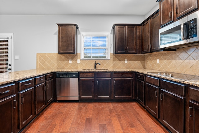 kitchen featuring backsplash, dark wood-type flooring, sink, light stone countertops, and appliances with stainless steel finishes