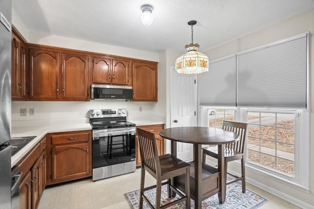 kitchen featuring pendant lighting, a textured ceiling, and appliances with stainless steel finishes