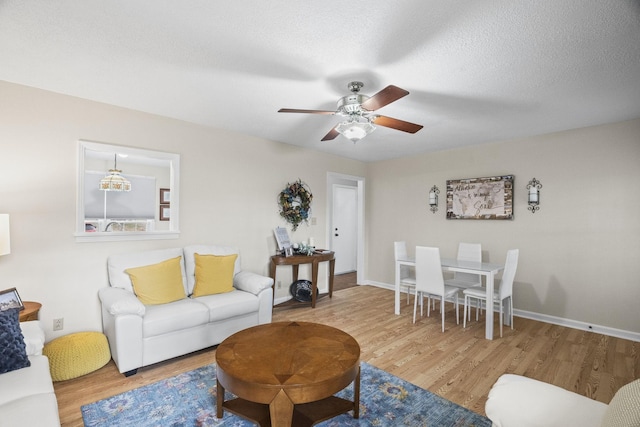 living room with hardwood / wood-style flooring, ceiling fan, and a textured ceiling