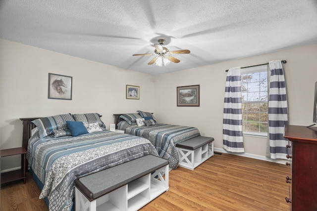 bedroom with a textured ceiling, hardwood / wood-style flooring, and ceiling fan