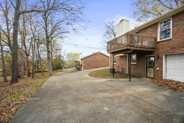 view of property exterior featuring a garage, cooling unit, and a wooden deck