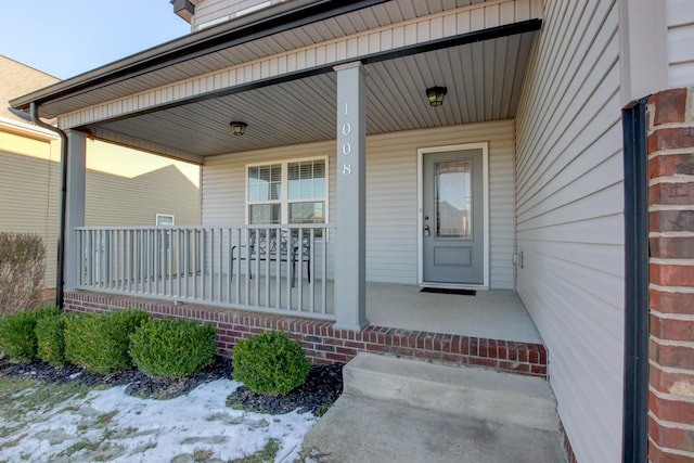 snow covered property entrance featuring covered porch