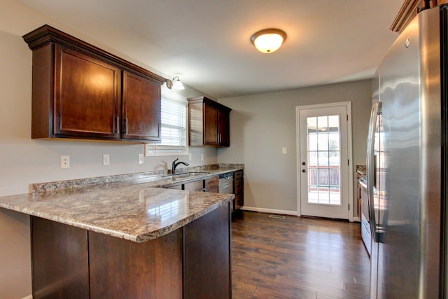 kitchen with dark hardwood / wood-style floors, kitchen peninsula, sink, appliances with stainless steel finishes, and light stone counters