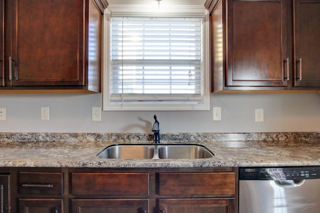 kitchen with stainless steel dishwasher, sink, and light stone counters