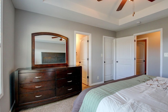 bedroom featuring ceiling fan, light colored carpet, and a raised ceiling