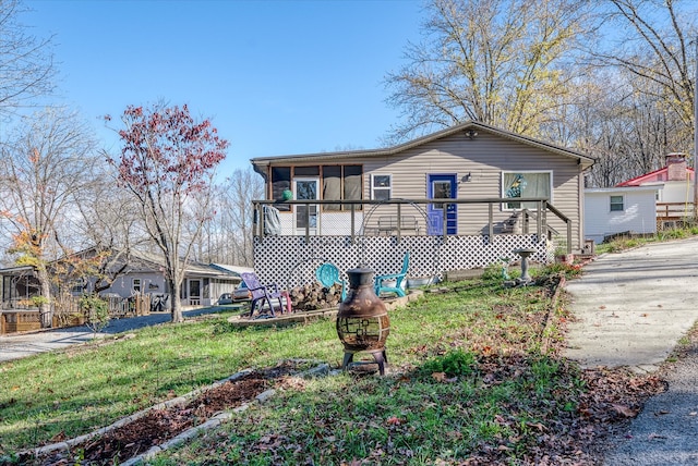 view of front of property featuring a sunroom and a front lawn