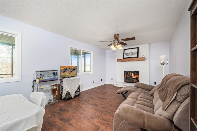 living room featuring plenty of natural light, dark hardwood / wood-style floors, a textured ceiling, and a brick fireplace