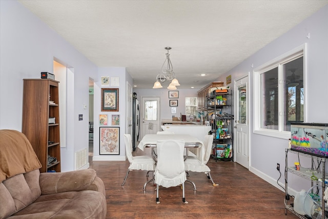 dining room featuring dark hardwood / wood-style flooring, a textured ceiling, and a notable chandelier