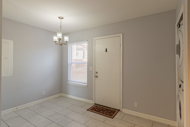 entrance foyer featuring a notable chandelier, light tile patterned floors, and stacked washer / dryer